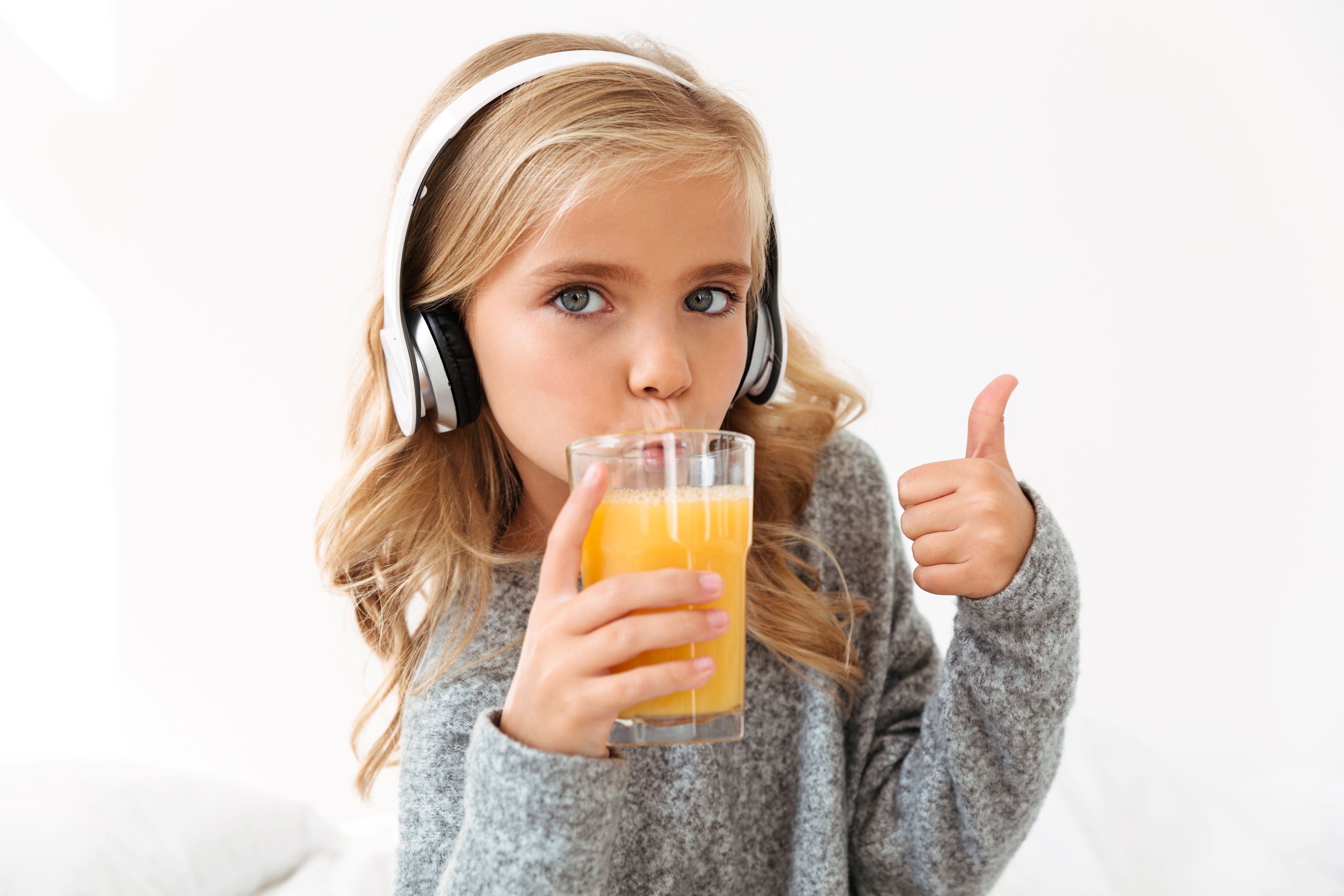 1785401656 Close Up Portrait Cute Girl Headphones Drinking Orange Juice Showing Thumb Up Gesture